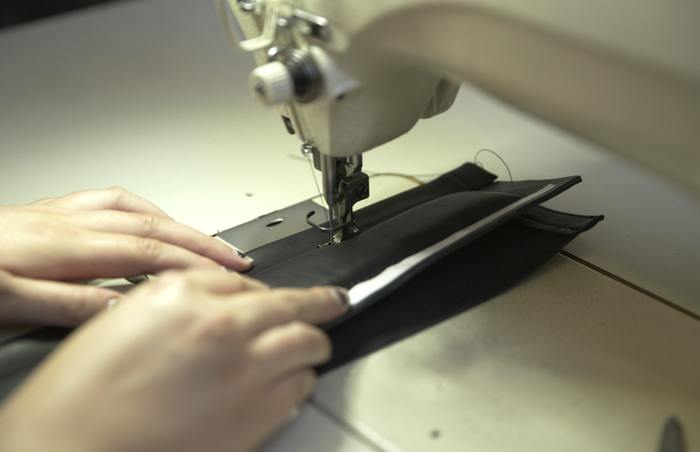 Hands machining a black panel on an industrial sewing machine