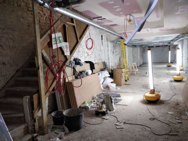 The Soho basement during the fit-out: bare brick, stacked boards, cables and work lights