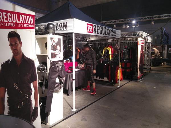 The REGULATION stall indoors under truss lighting, a visitor browsing the rails