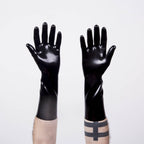 A pair of black latex rubber gloves worn on human hands against a white background
